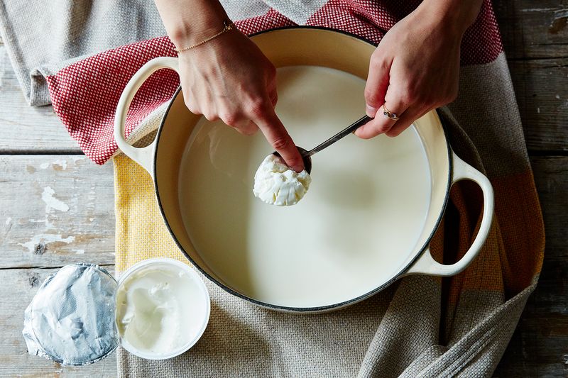 Adding starter (AKA yogurt you already have, whether store-bought or homemade from a previous batch) to the warm milk.