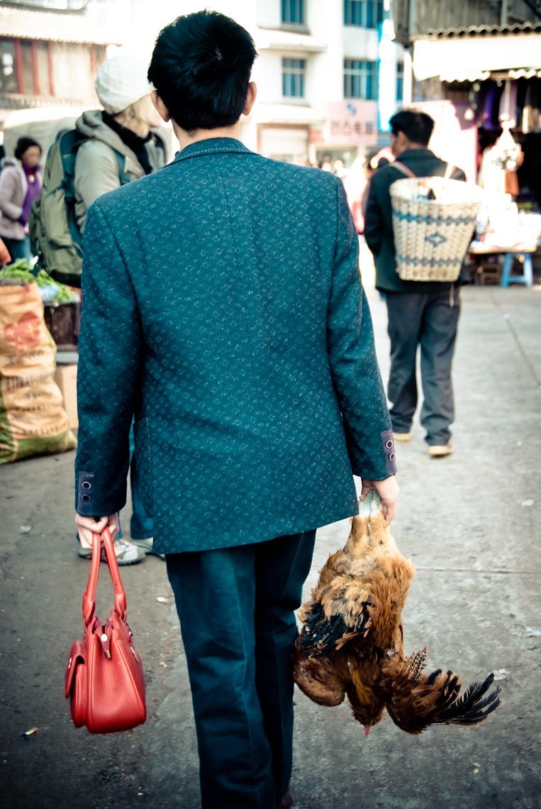 Man with red purse and live chicken, Li Jiang, Yunnan, China.