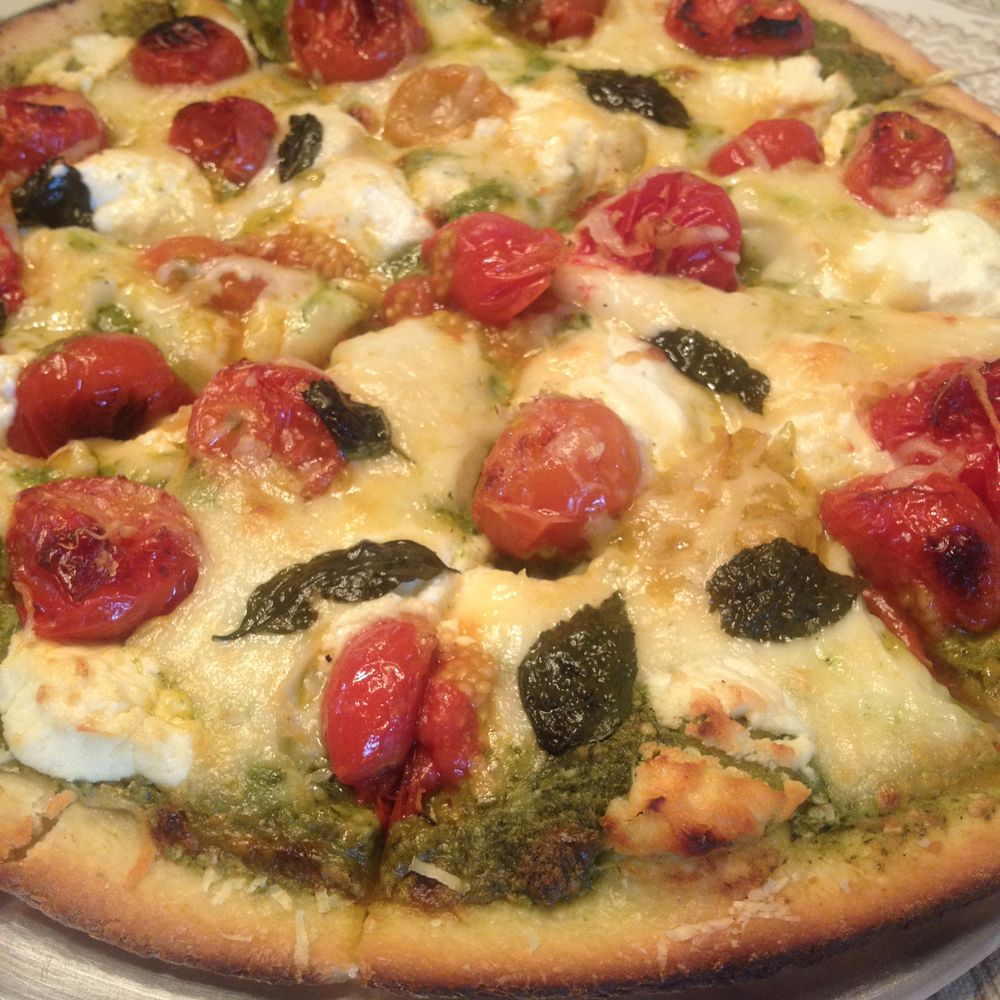 pesto pizza with roasted tomatoes, homemade ricotta, and caramelized onions